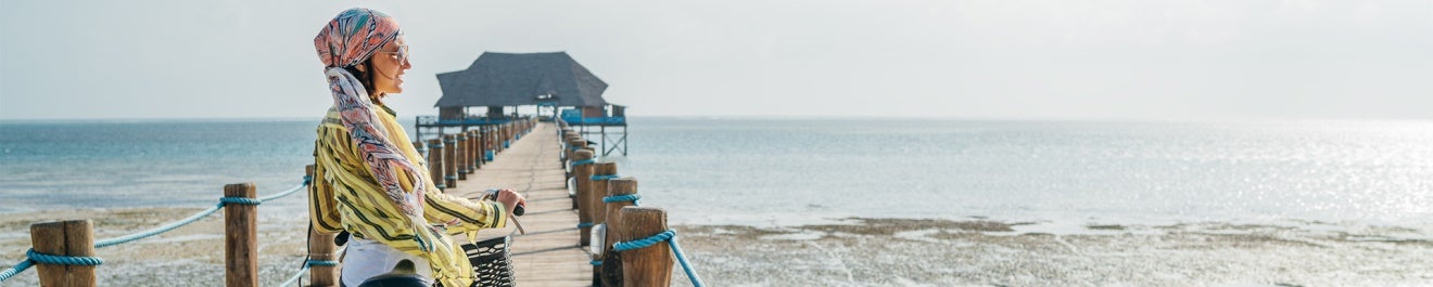 Une femme sur son vélo sur un ponton allant à la mer